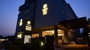 A hotel with a modern facade, illuminated signage, and a covered entrance area. - Hotel Grand Serene Mysore (Mysore)