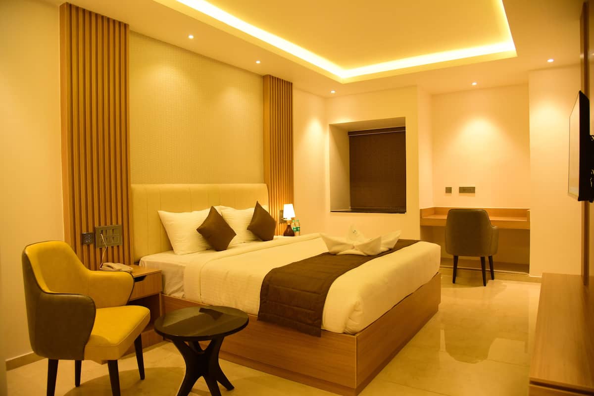 Una habitación de hotel con una cama grande, un escritorio, una silla y una mesita.