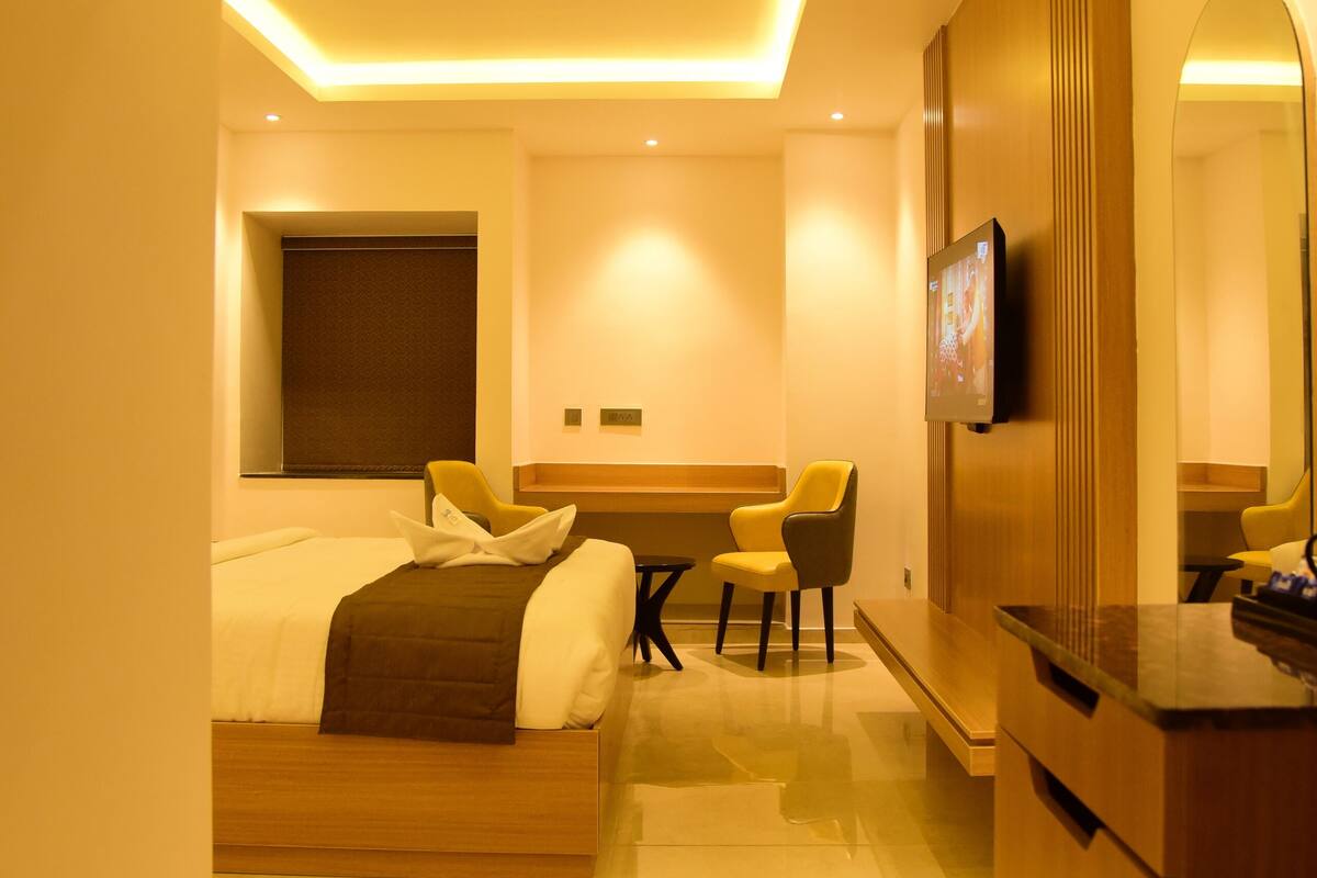 Una habitación de hotel moderna con una cama, un escritorio, una silla, un televisor y un espejo.