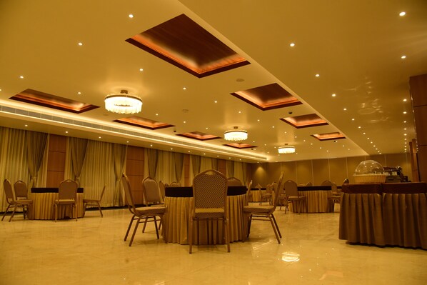Un amplio salón de banquetes con techos altos, iluminación empotrada y una lámpara central.