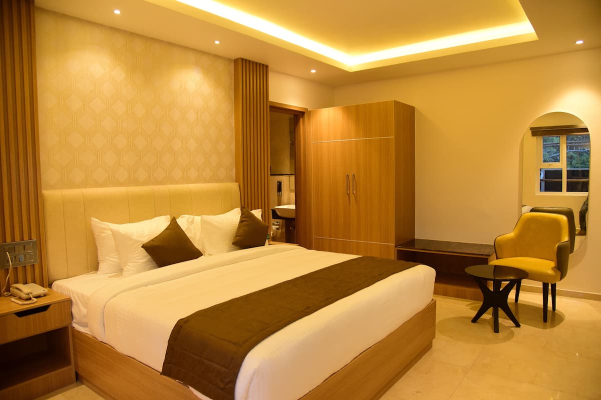 Una habitación de hotel con una cama grande, un armario de madera, una mesita y una silla.