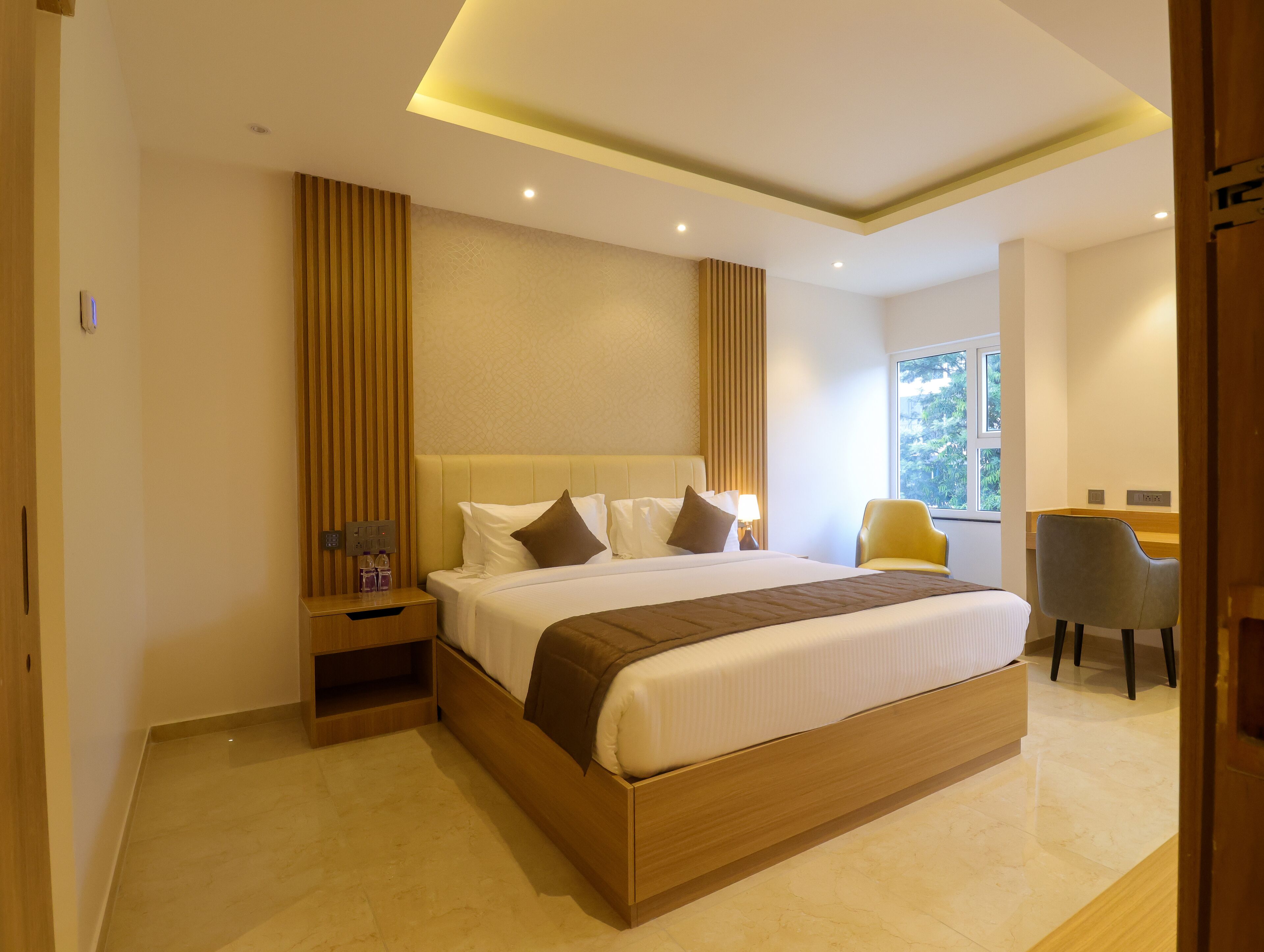 Een moderne hotelkamer met een groot bed, nachtkastjes, een bureau en een stoel.