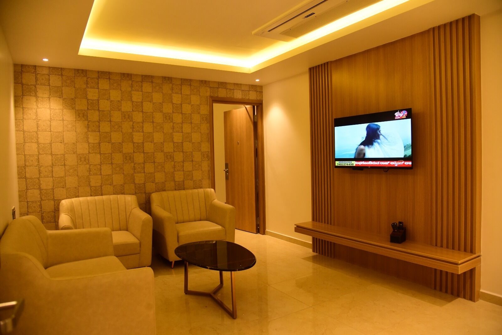 Una sala de estar moderna con dos sofás, una mesa de centro y un televisor de pantalla plana montado en una pared de paneles de madera.