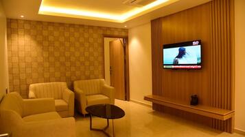 Una sala de estar moderna con dos sofás, una mesa de centro y un televisor de pantalla plana montado en una pared de paneles de madera.