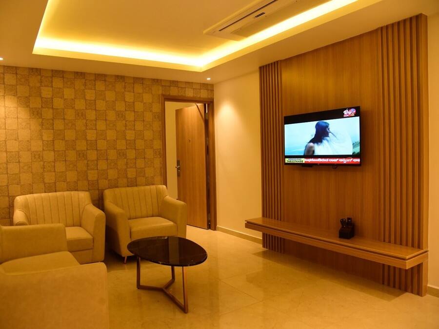 Uma sala de estar moderna com dois sofás, uma mesa de centro e uma televisão de tela plana fixada em uma parede de painéis de madeira.