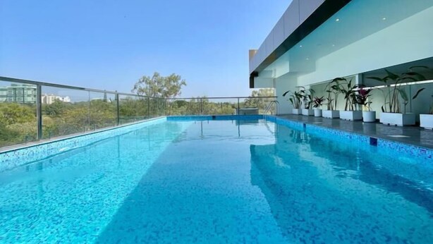 A modern infinity pool with a clear view of the sky and surrounding greenery. - Hotel Grand Serene Mysore (Mysore)