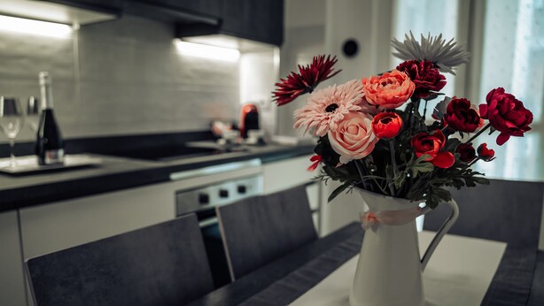 Una cucina moderna con un tavolo da pranzo apparecchiato per due persone, con un vaso di fiori e un bicchiere d'acqua.
