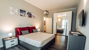 Una camera da letto moderna con un letto, comodini, una cassettiera e una TV.