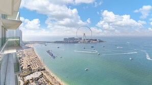 Un paysage urbain côtier avec une plage, un port de plaisance et une grande grande roue.