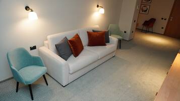 Un salón moderno con un sofá blanco, sillones estampados y una alfombra de diseño geométrico.