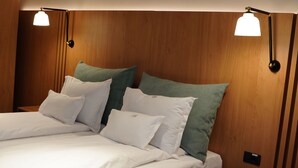 A neatly made bed with white and green pillows, wooden headboard, and two wall-mounted lamps. - Hotel Sorin Mihai (Crizbav)