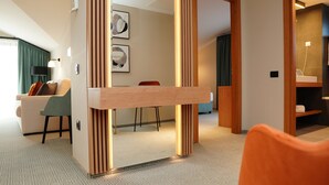 A modern hotel room with a wooden partition, a sofa, a dining table, and a view of the hallway. - Hotel Sorin Mihai (Crizbav)