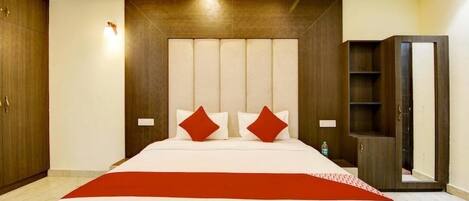 A hotel room with a large bed, a wardrobe, and a mirror.