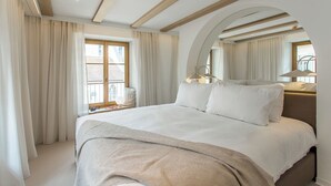 Une chambre d’hôtel moderne avec un grand lit, une fenêtre avec des rideaux, une table de chevet avec une lampe et un miroir.