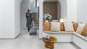 Un intérieur moderne avec un coin salon, un escalier et une personne portant des bagages.