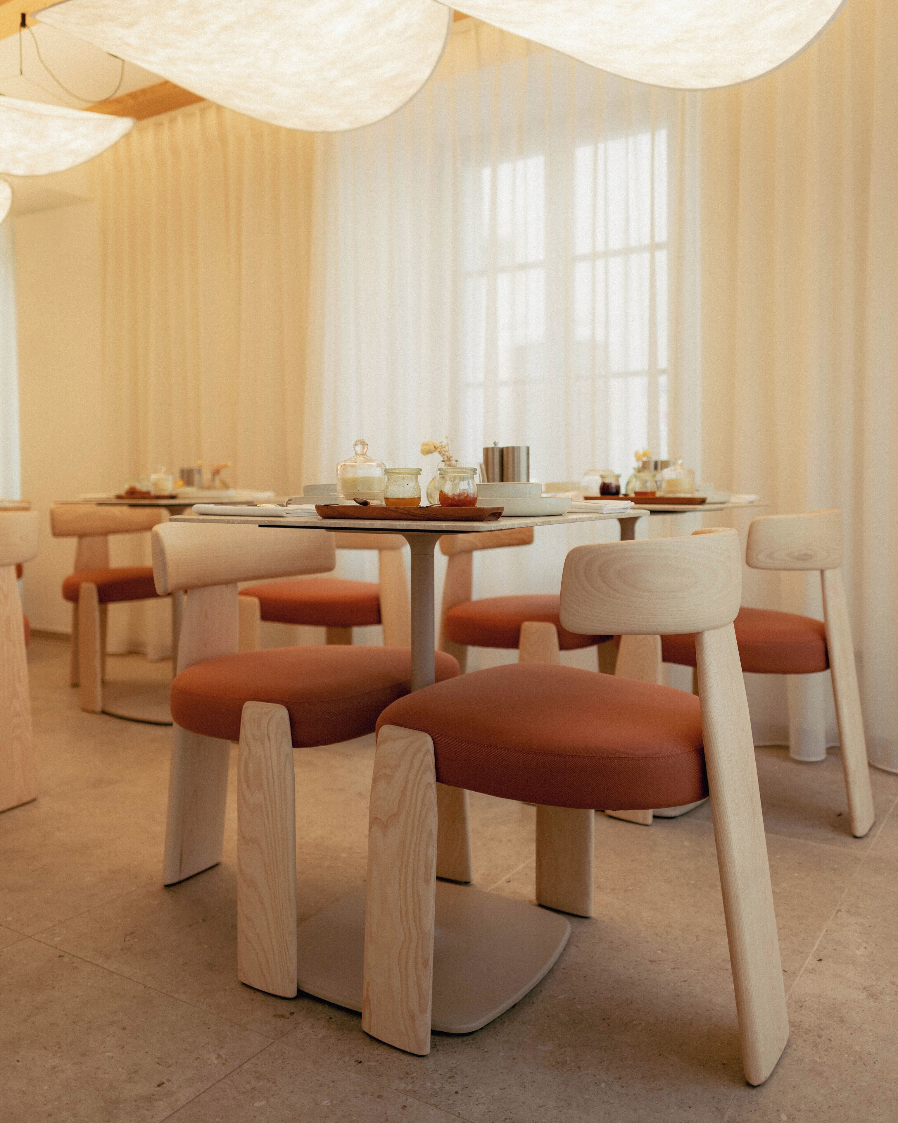 Un comedor moderno con sillas y mesas de madera, con un diseño limpio y minimalista.