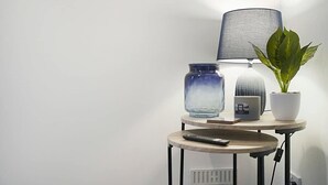 A small round table with a lamp, a potted plant, and a remote control. - Seaside Haven on Newcomen Grove, Redcar Retreat (Redcar and Cleveland)