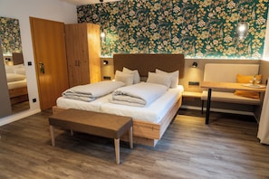 Une chambre à coucher avec un lit double, un banc, une armoire en bois et un autre banc avec un coussin.