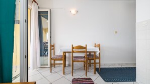 A dining area with a table and chairs, a patterned rug, and a sliding glass door leading to an outdoor area.