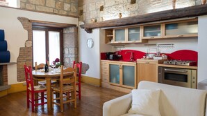 A cozy kitchen with a red countertop, wooden cabinets, and a built-in oven. - Suite Apartment Voltumna (Orvieto)