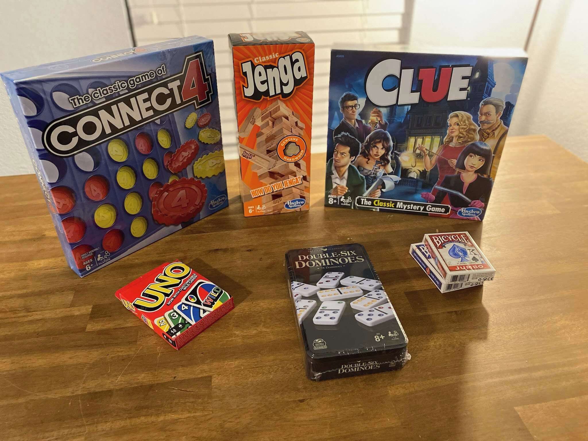 A table with various board games including Connect 4, Jenga, Clue, UNO, and Dominoes.