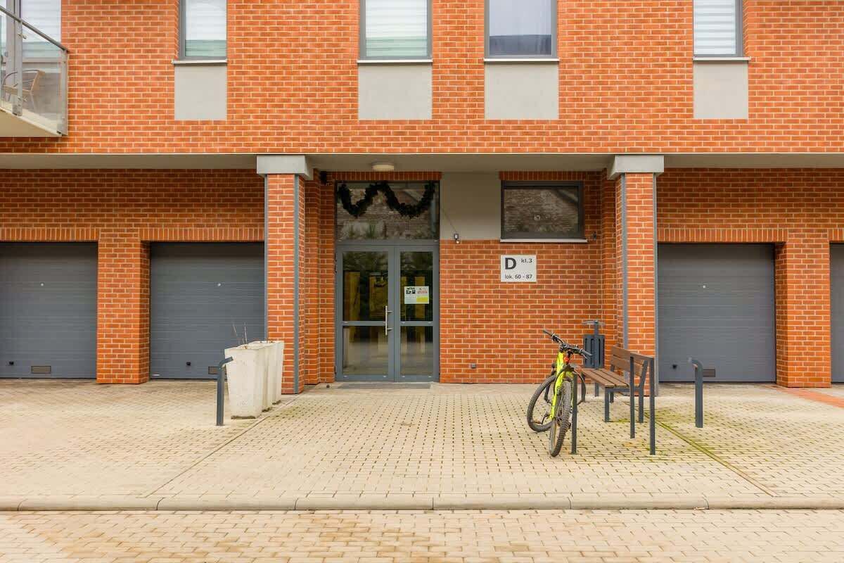 A brick building with a garage door labeled 'D', a bicycle, and a bench.