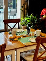 A dining table with a green placemat, a potted plant, and a variety of food items.