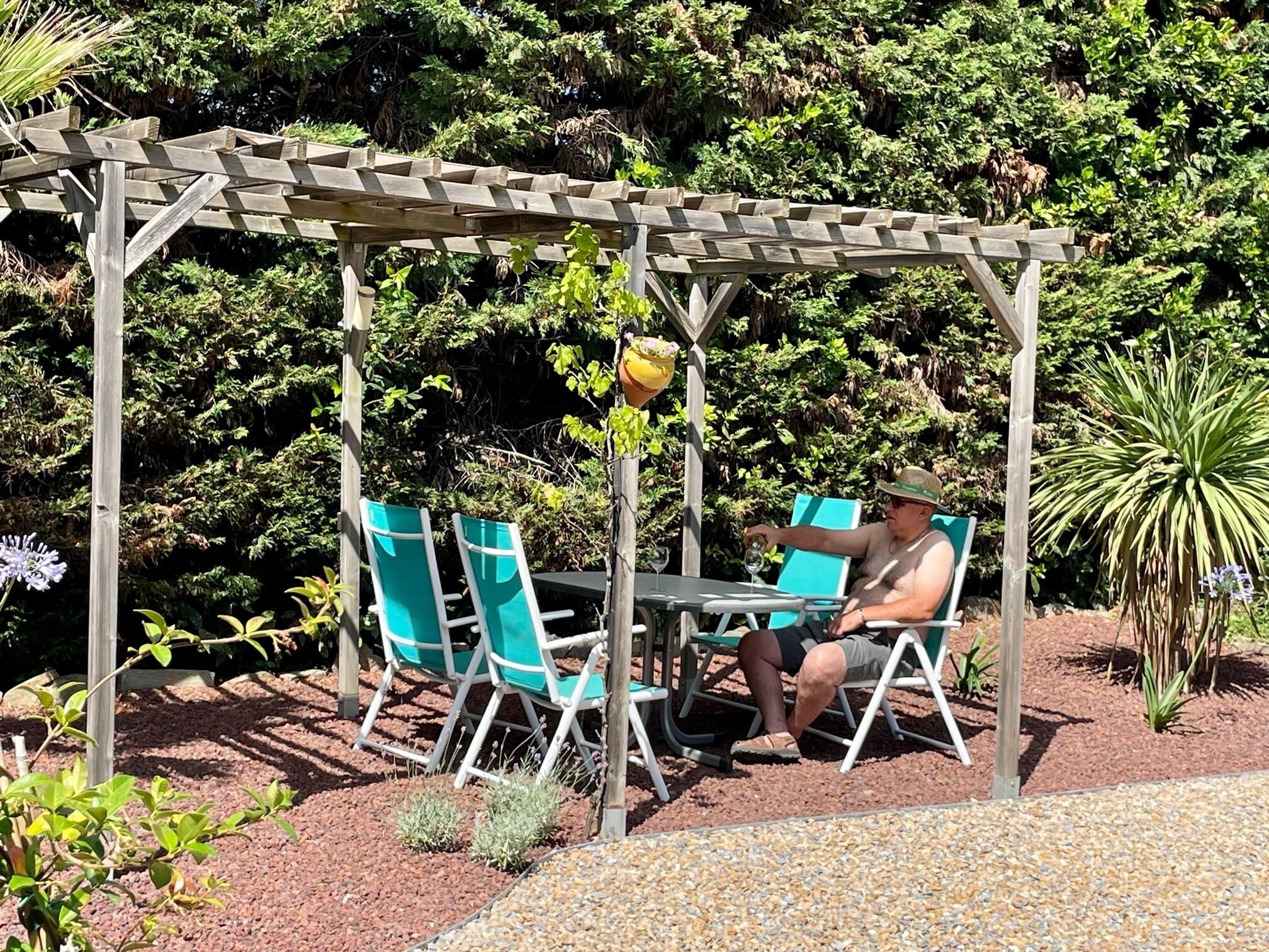 Ein hölzerner Pergola mit Tisch und Stühlen in einem Garten.