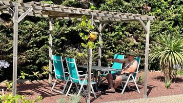 Ein hölzerner Pergola mit Tisch und Stühlen in einem Garten.