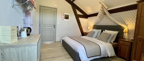 A bedroom with a bed, bedside tables, a nightstand, a wardrobe, a wooden floor, a ceiling fan, and a wall-mounted towel rack.