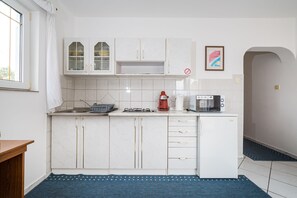 A kitchen with white cabinets, a stove, a coffee maker, and a microwave. - Nice Apartment Silvia 2 for 4 Persons (Novalja)