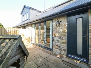 A stone exterior wall with a black door and windows.