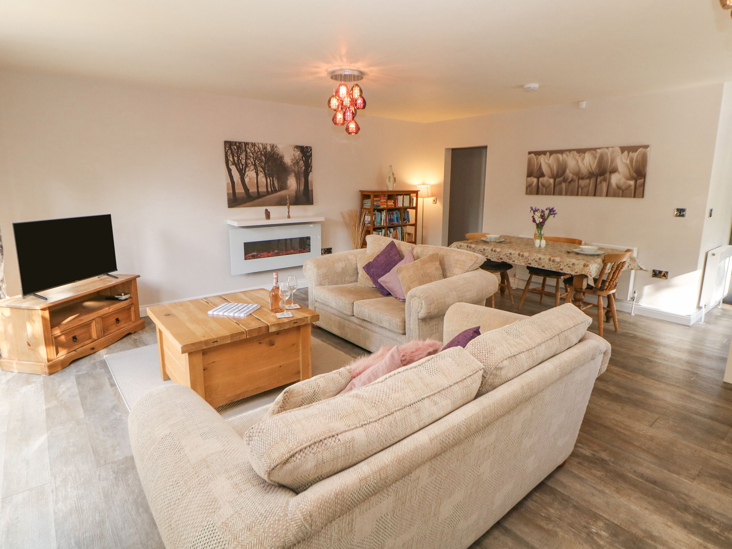 A living room with a sofa, coffee table, TV, fireplace, bookshelf, dining table, and chairs.