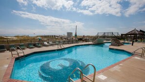 A swimming pool with a circular pattern in the center, surrounded by lounge chairs and a covered area with stairs. - Phoenix East 008 by Liquid Life (Orange Beach)