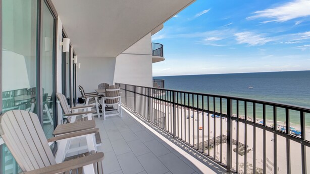 A balcony with a view of the beach and ocean, featuring outdoor seating and a railing. - Phoenix IX 1101 by Liquid Life (Orange Beach)