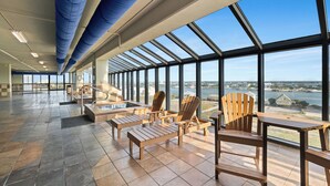 A spacious indoor area with large windows, wooden chairs, and a view of a body of water. - Phoenix IX 1101 by Liquid Life (Orange Beach)