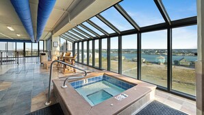 A large indoor swimming pool with a view of a body of water and buildings, surrounded by large windows and a high ceiling. - Phoenix IX 1101 by Liquid Life (Orange Beach)