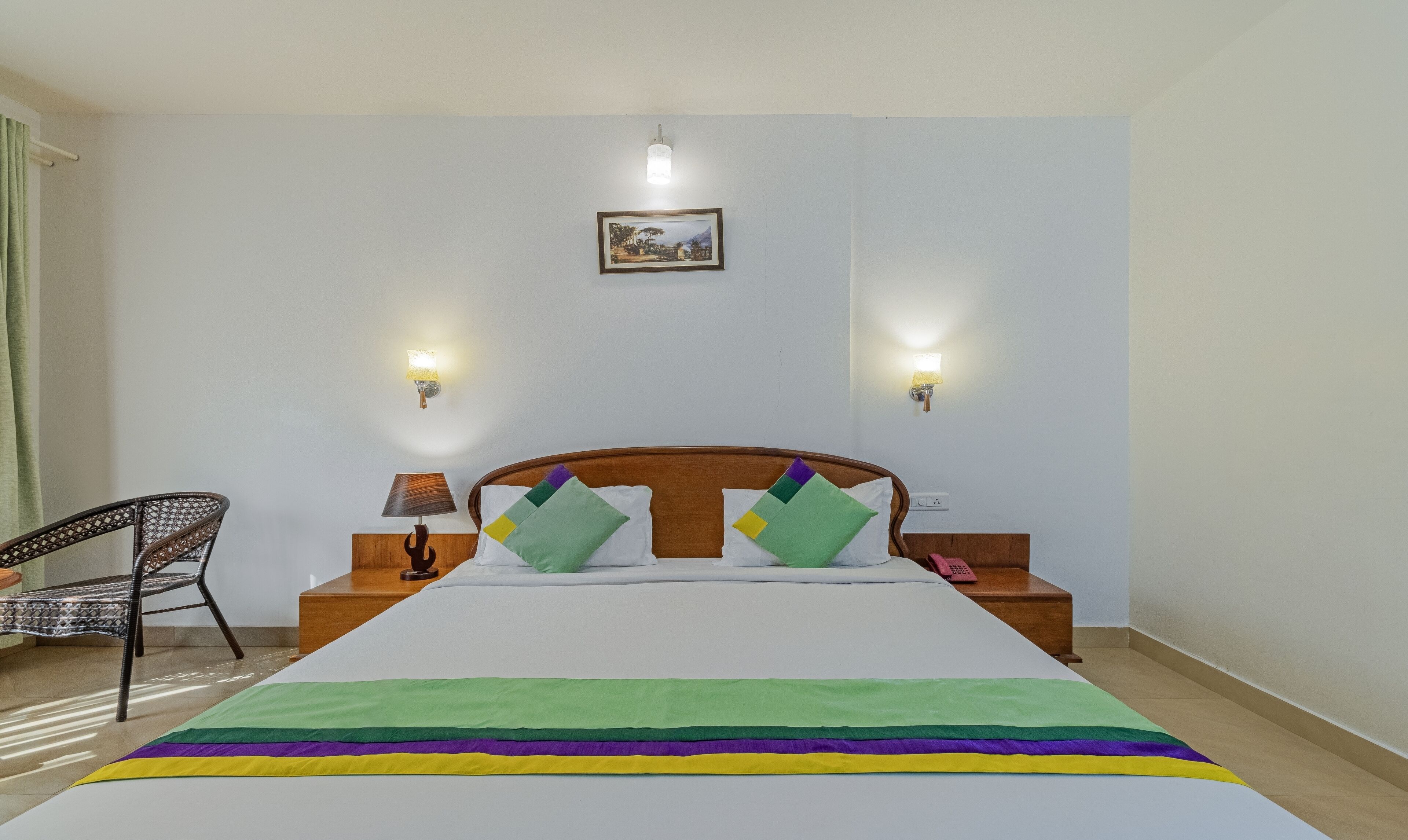 A neatly arranged hotel room with a large bed, two bedside tables, a chair, and two wall-mounted lamps.