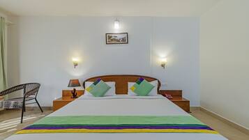 A neatly arranged hotel room with a large bed, two bedside tables, a chair, and two wall-mounted lamps.