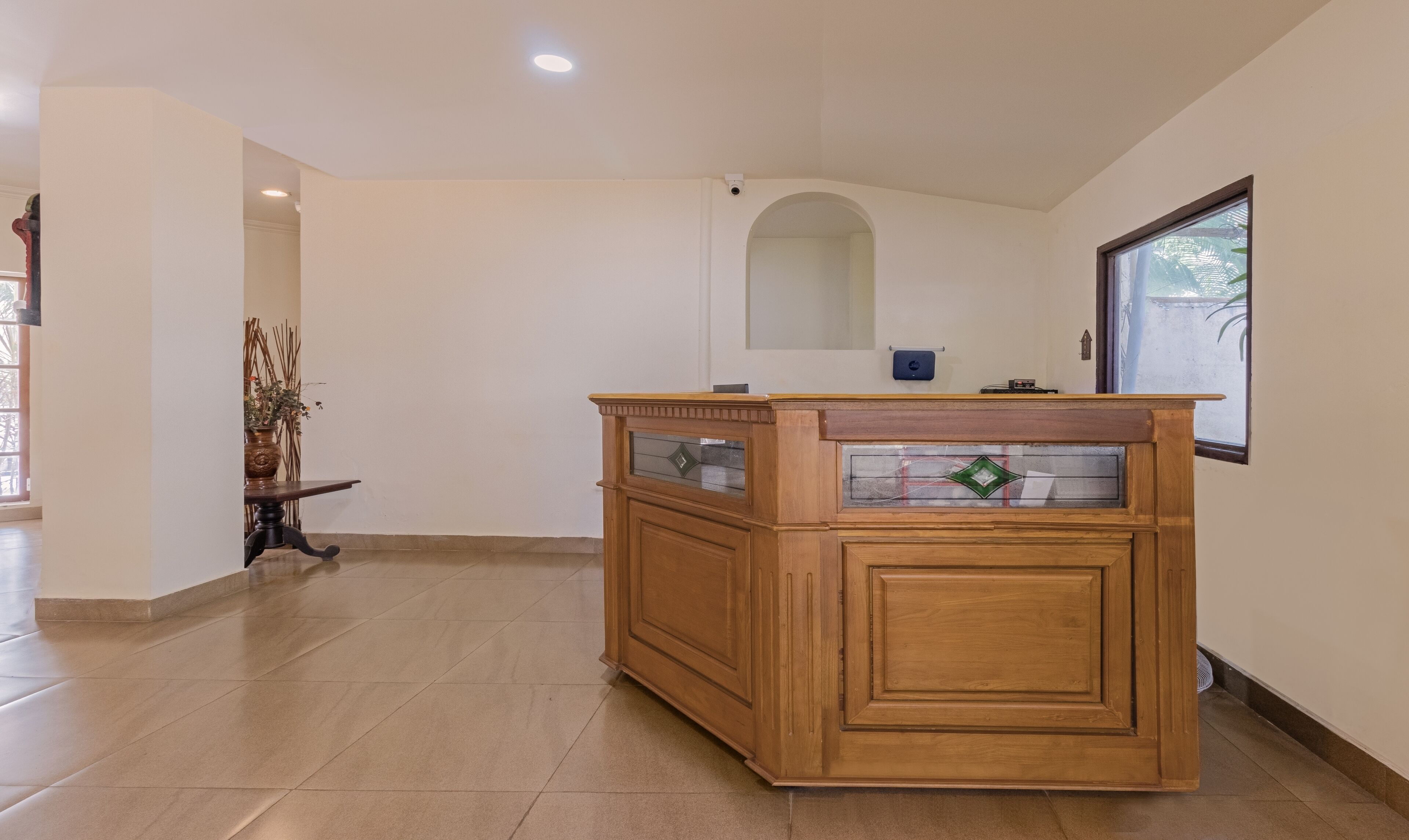 A wooden reception desk with glass panels and a small mirror.