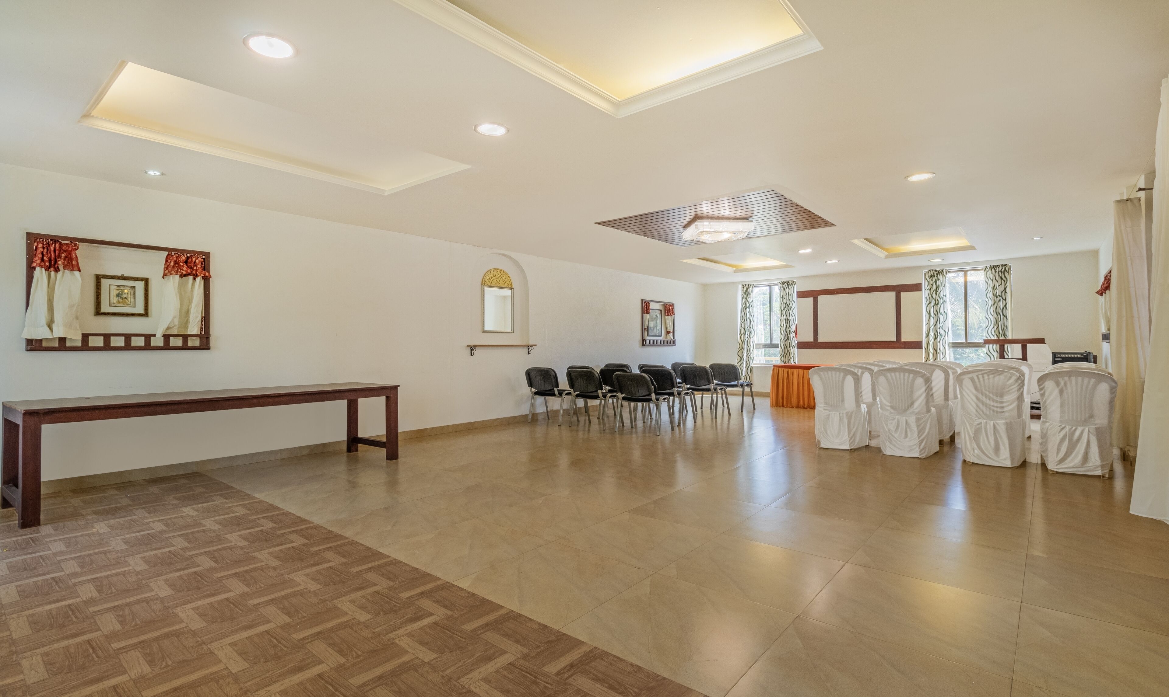 A spacious room with a wooden bench, rows of chairs, and a table with a tablecloth.