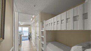 A room with bunk beds, a door leading to a balcony, and a view of the ocean. - Royal Palms 703 by Liquid Life (Gulf Shores)