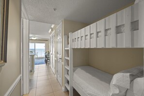 Una habitación con literas, una puerta que da a un balcón y vista al océano.