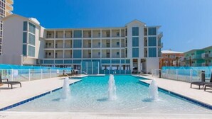 A hotel with a swimming pool, multiple balconies, and a clear blue sky. - Sea Glass 406 by Liquid Life (Gulf Shores)