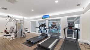 A gym with treadmills, weight machines, and a TV screen. - Summer House 304B by Liquid Life (Orange Beach)