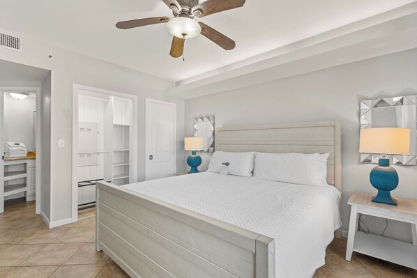 Een slaapkamer met een bed, twee bedlampen, een plafondventilator, een kledingkast en een spiegel aan de muur.