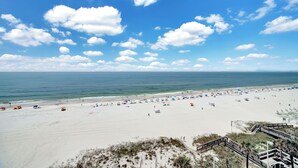 A beach with a clear sky, sandy shore, and a wooden boardwalk leading to the water. - Tradewinds 701 by Liquid Life (Orange Beach)