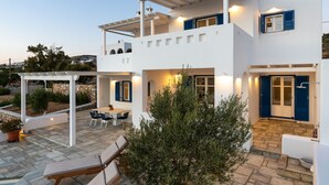 Une maison à deux étages avec un patio, un espace salon extérieur et un petit jardin.