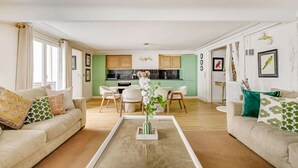 A living room with a coffee table, sofas, and a kitchen in the background.