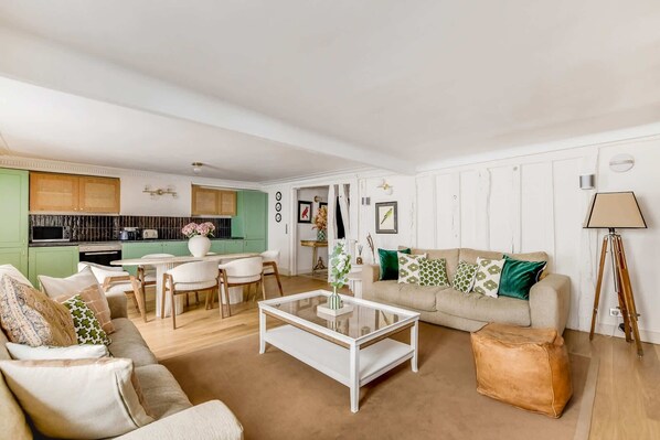 A living room with a sofa, coffee table, and a dining area with chairs and a table. - A Breathtaking 2BR/2Ba in Opera (Paris)